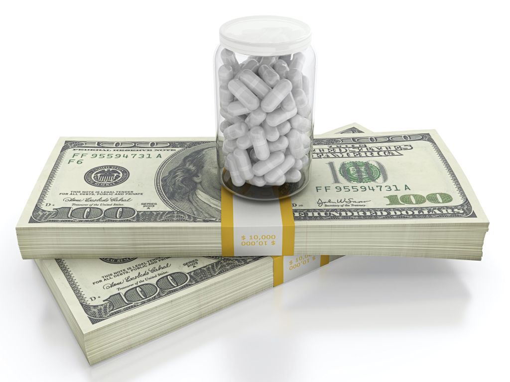 White pills on top of dollar bills bundle. High cost of healthcare concept