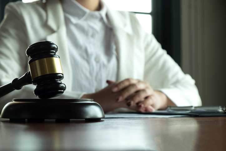 Midsection Of Female Judge With Gavel At Desk In Courthouse