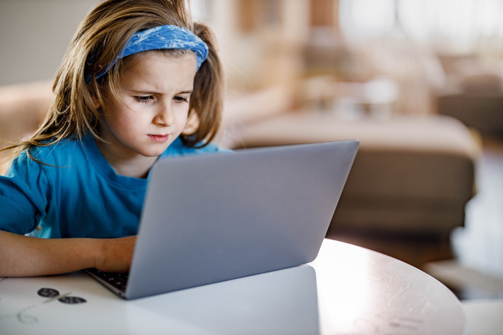 Little boy surfing the Internet on laptop at home.