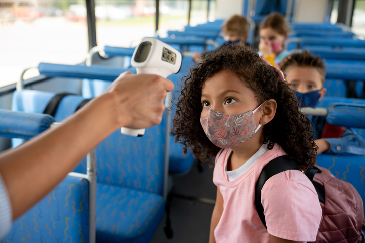 Girl getting her temperature checked on the school bus