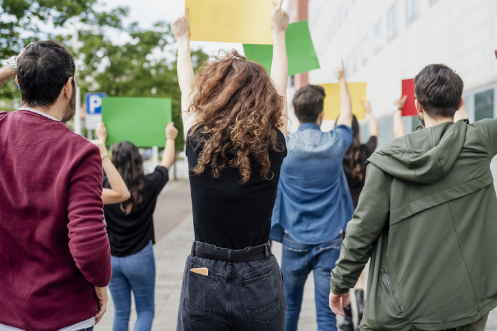 Multi ethnic activists holding banners while protesting on street in city